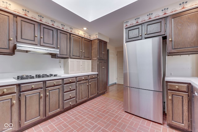 8903 Maple Hill Dr, Indianapolis, IN 46239 - kitchen with freestanding refrigerator, brick patterned flooring, light countertops, under cabinet range hood, and gas stovetop