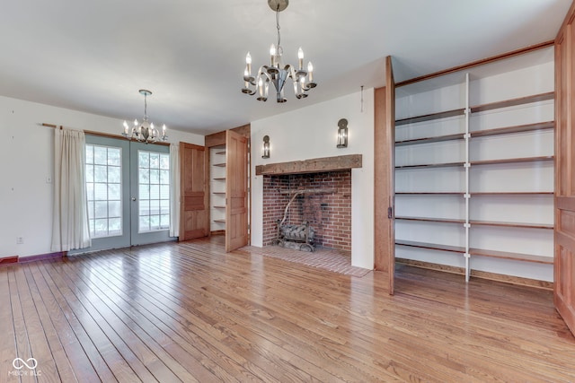8903 Maple Hill Dr, Indianapolis, IN 46239 - unfurnished living room featuring a chandelier, light wood-style floors, baseboards, and french doors