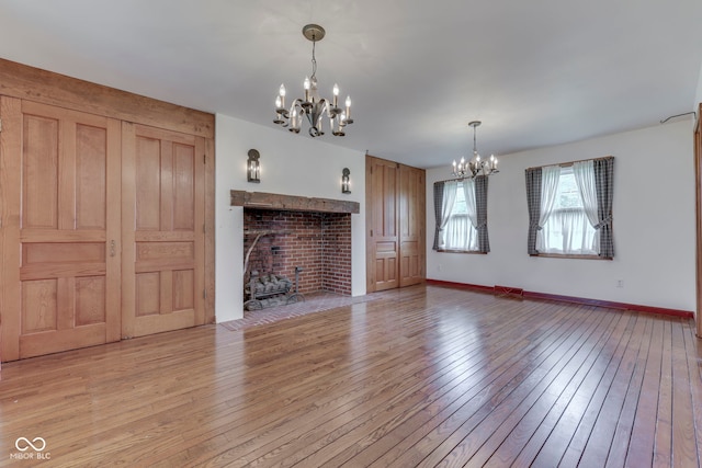 8903 Maple Hill Dr, Indianapolis, IN 46239 - unfurnished living room with a chandelier, light wood finished floors, a fireplace, and baseboards
