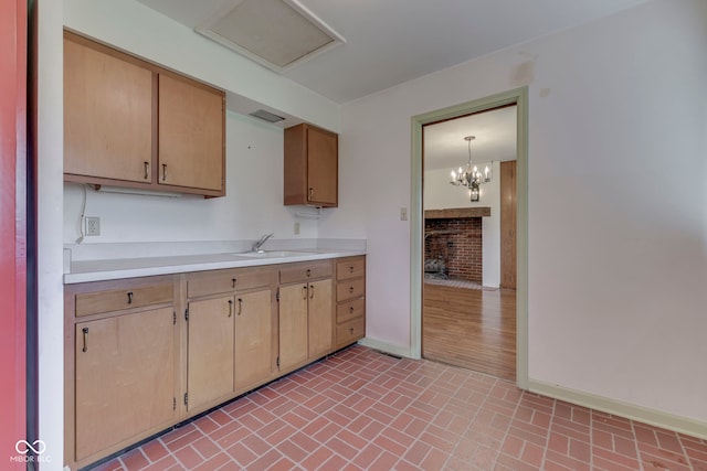 8903 Maple Hill Dr, Indianapolis, IN 46239 - kitchen featuring a sink, light countertops, baseboards, brick patterned floors, and a chandelier