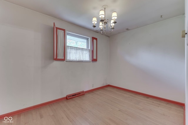 8903 Maple Hill Dr, Indianapolis, IN 46239 - empty room with light wood-style flooring, a chandelier, and baseboards