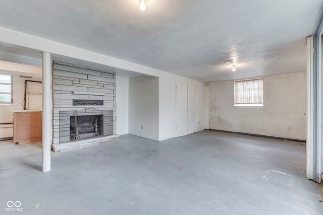 8903 Maple Hill Dr, Indianapolis, IN 46239 - unfurnished living room with concrete flooring, healthy amount of natural light, a stone fireplace, and concrete block wall