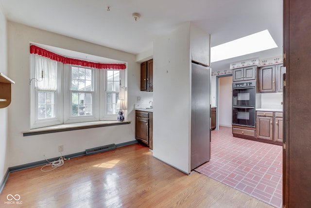 8903 Maple Hill Dr, Indianapolis, IN 46239 - kitchen with stainless steel refrigerator, light countertops, baseboards, and a skylight