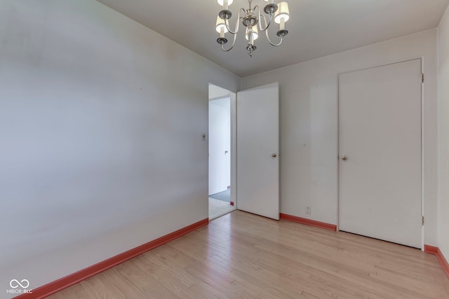 8903 Maple Hill Dr, Indianapolis, IN 46239 - unfurnished room with light wood finished floors, baseboards, and a chandelier