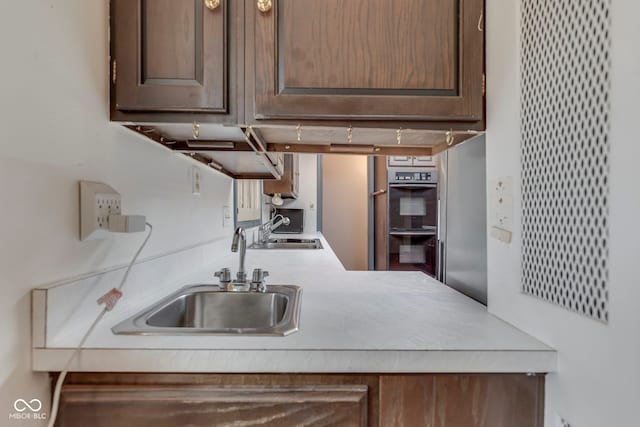 8903 Maple Hill Dr, Indianapolis, IN 46239 - kitchen featuring a sink, double wall oven, light countertops, and dark brown cabinets