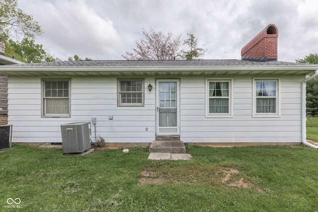 8903 Maple Hill Dr, Indianapolis, IN 46239 - back of property featuring central AC unit, a chimney, a yard, and a shingled roof