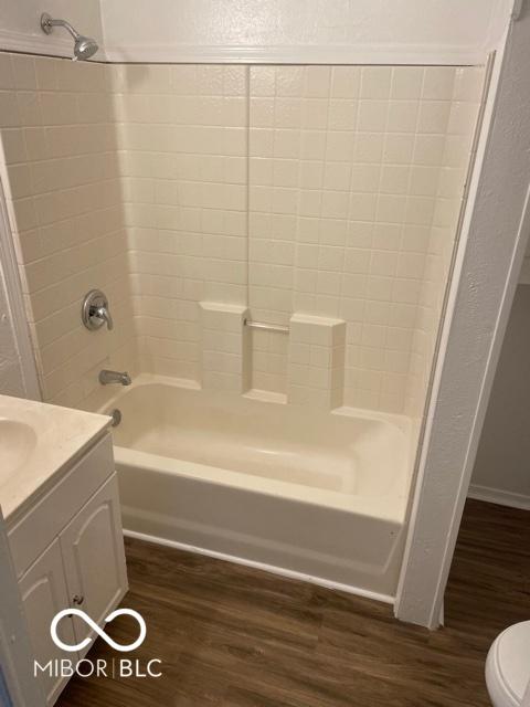 bathroom featuring vanity, toilet, bathtub / shower combination, and wood finished floors
