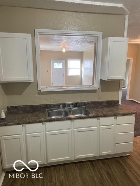 kitchen with a sink, dark countertops, white cabinetry, and dark wood-style floors