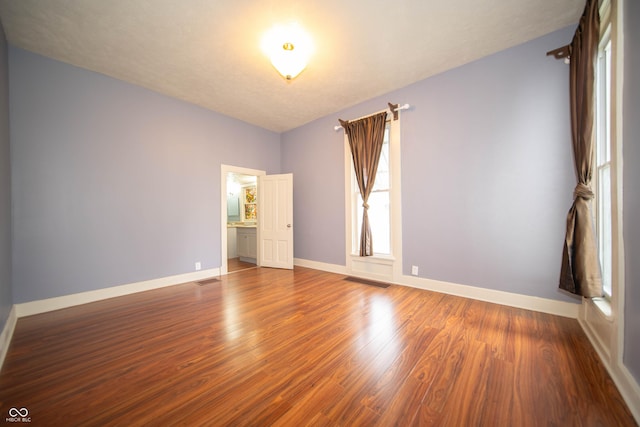 empty room featuring baseboards, visible vents, and wood finished floors