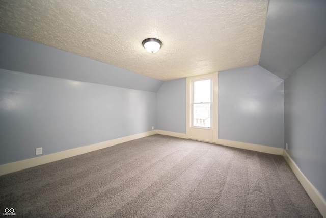 additional living space featuring lofted ceiling, a textured ceiling, carpet flooring, and baseboards