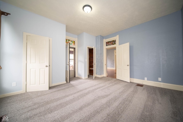 unfurnished bedroom with baseboards, visible vents, and carpet