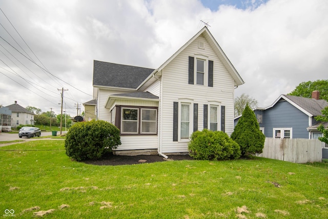 view of front of property with fence, a shingled roof, and a front yard