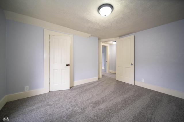 unfurnished bedroom featuring a textured ceiling, carpet, and baseboards