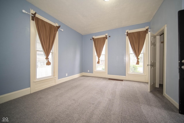spare room featuring a wealth of natural light, carpet, baseboards, and visible vents
