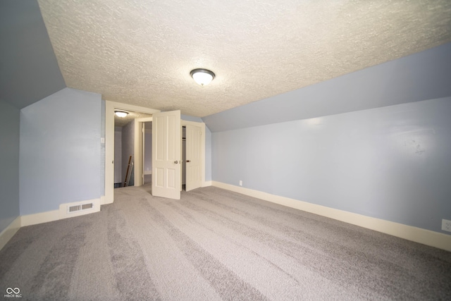 bonus room with baseboards, lofted ceiling, visible vents, and a textured ceiling