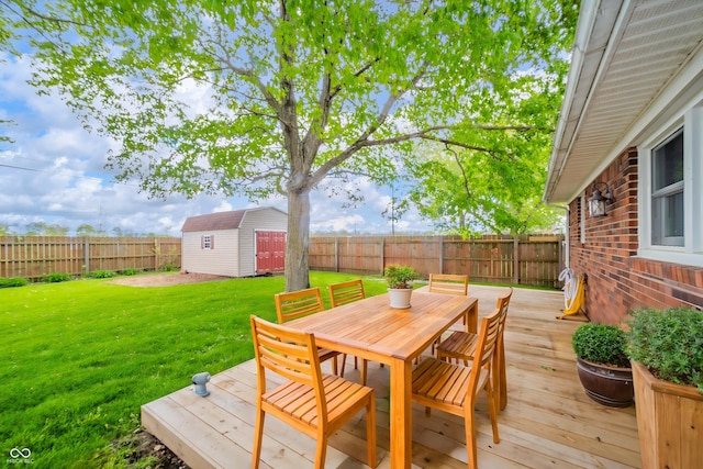 wooden deck featuring a yard, a fenced backyard, outdoor dining space, an outdoor structure, and a storage shed
