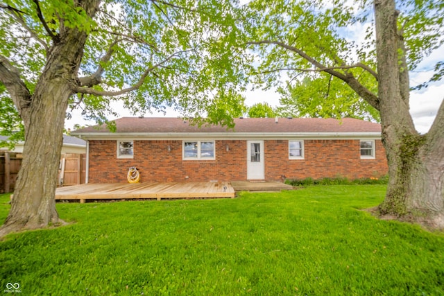 back of property featuring a yard, a wooden deck, brick siding, and fence