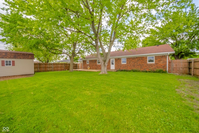 view of yard with a fenced backyard, an outdoor structure, and a shed