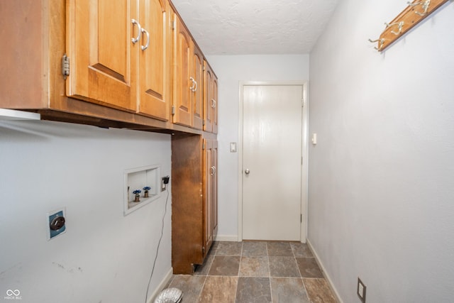 clothes washing area with cabinet space, washer hookup, hookup for an electric dryer, a textured ceiling, and baseboards