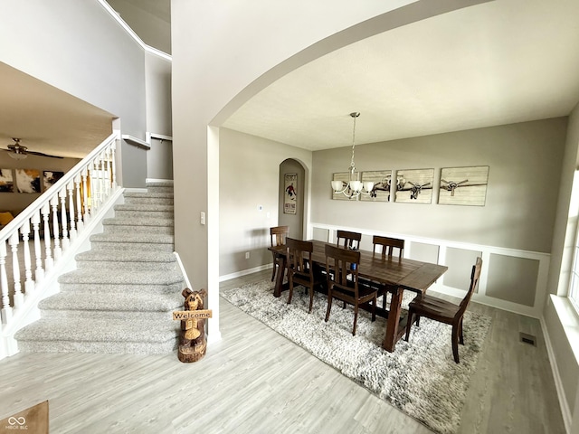 dining room featuring a notable chandelier, visible vents, stairs, wood finished floors, and arched walkways