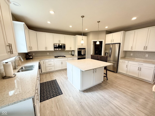 kitchen with a sink, decorative backsplash, a kitchen island, stainless steel appliances, and white cabinets