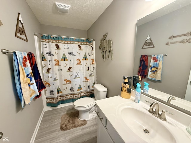 bathroom featuring toilet, wood finished floors, a textured ceiling, visible vents, and vanity