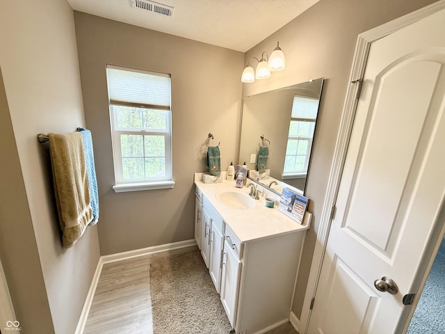 bathroom featuring wood finished floors, visible vents, baseboards, and vanity