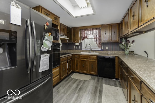 3134 W Hickory Woods Dr, Greenfield, IN 46140 - kitchen with black appliances, a sink, under cabinet range hood, light wood-type flooring, and light countertops
