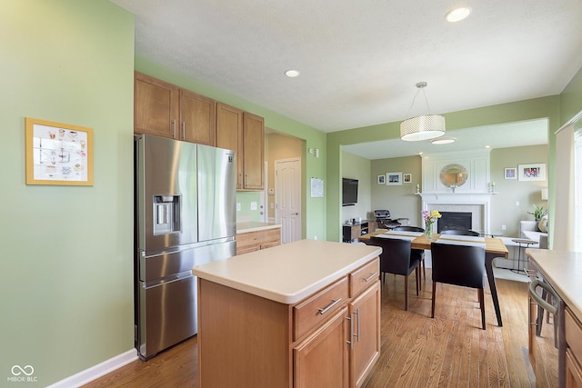 6839 Powder Dr, Indianapolis, IN 46259 - kitchen with stainless steel fridge with ice dispenser, wood finished floors, light countertops, open floor plan, and pendant lighting