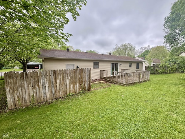 rear view of house with fence, a lawn, and a deck