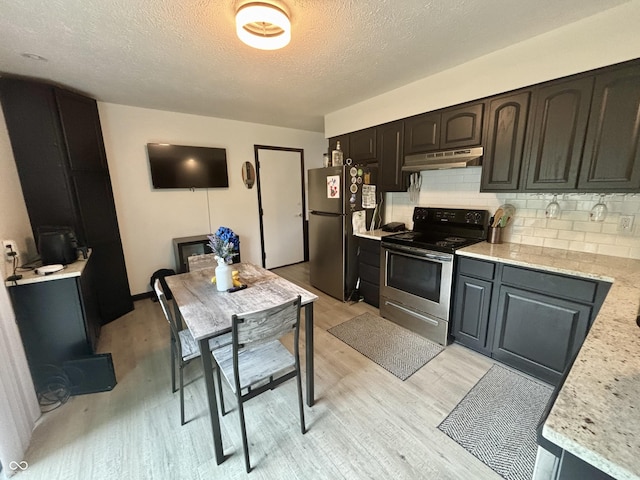 kitchen with stainless steel appliances, a textured ceiling, light wood-type flooring, under cabinet range hood, and decorative backsplash