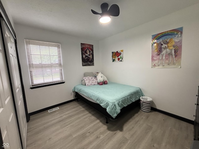 bedroom featuring baseboards, light wood-style floors, a closet, and visible vents