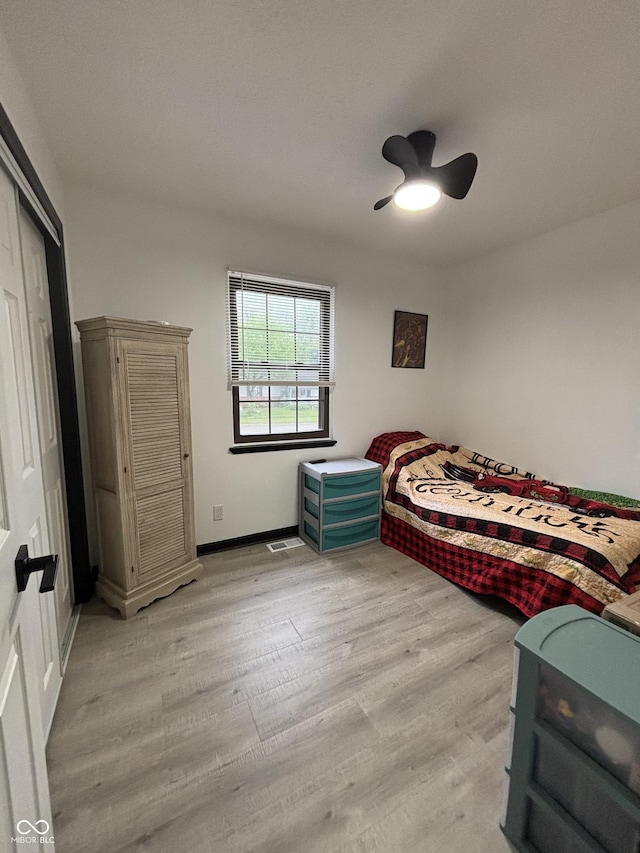bedroom with a closet, baseboards, light wood-style flooring, and a ceiling fan