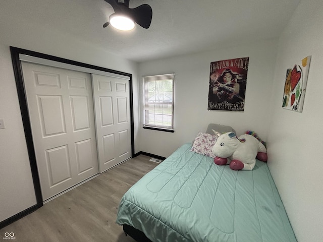 bedroom featuring a closet, baseboards, wood finished floors, and a ceiling fan