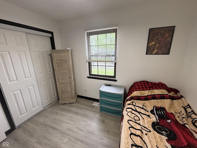 bedroom featuring light wood finished floors, a closet, baseboards, and visible vents