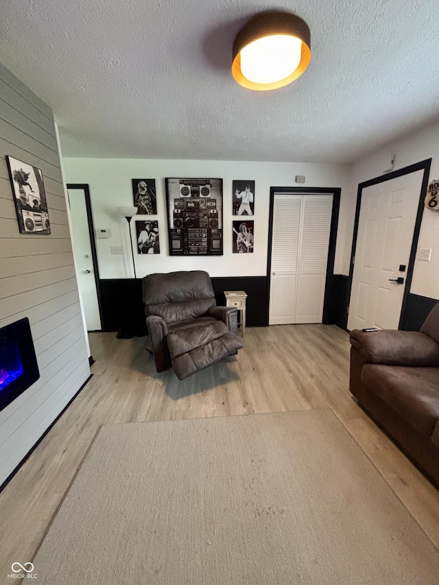 living room featuring a fireplace, a textured ceiling, and wood finished floors