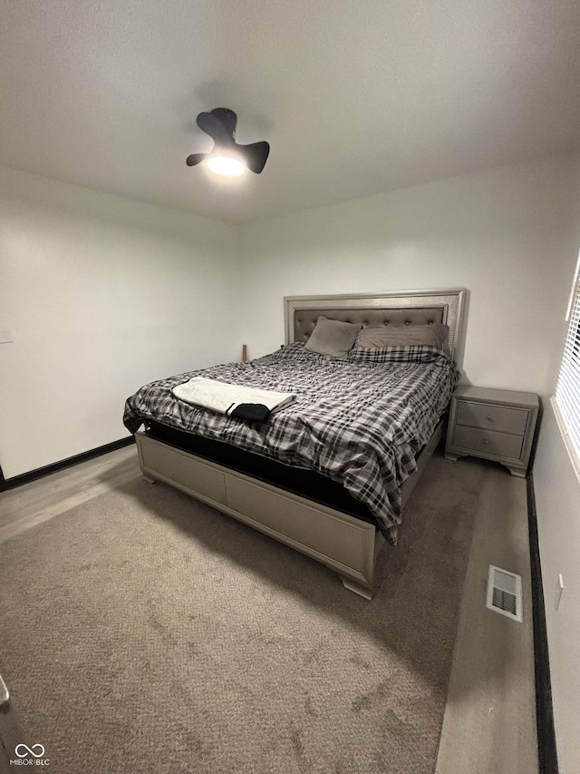 carpeted bedroom featuring baseboards, a ceiling fan, and visible vents