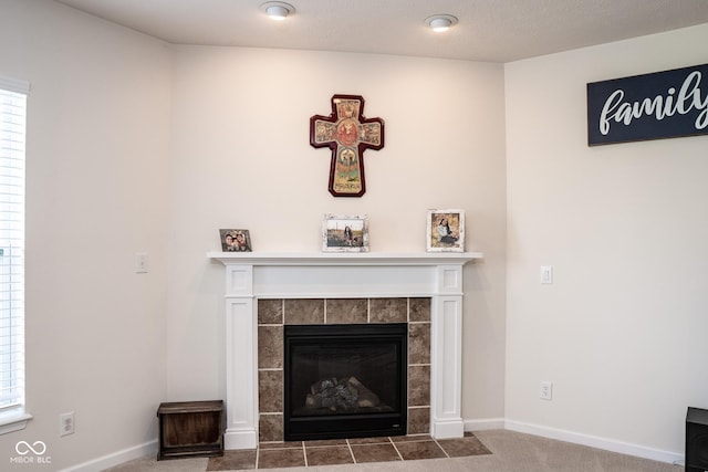 detailed view of a tiled fireplace, carpet floors, and baseboards