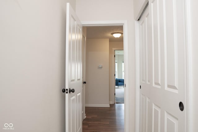 hallway featuring dark wood-style flooring and baseboards