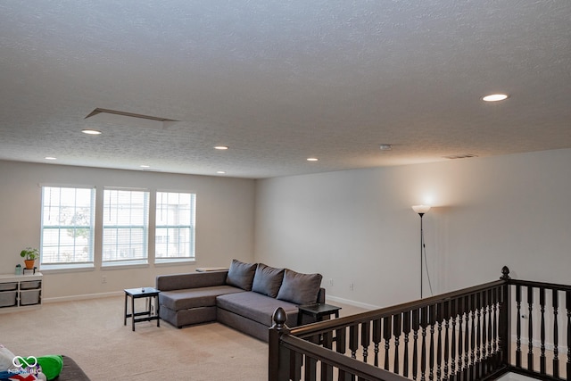living area with recessed lighting, light carpet, a textured ceiling, and baseboards