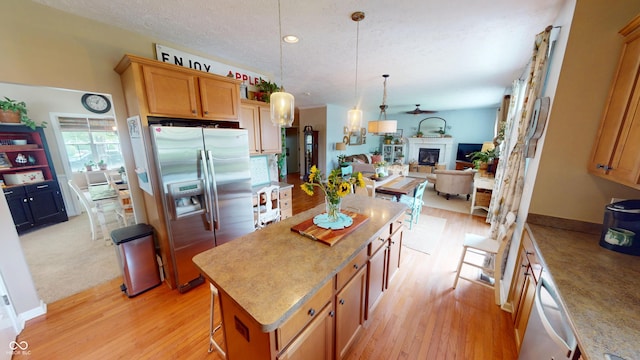 18247 Kinder Oak Dr, Noblesville, IN 46062 - kitchen featuring appliances with stainless steel finishes, open floor plan, light wood-style flooring, a center island, and a textured ceiling
