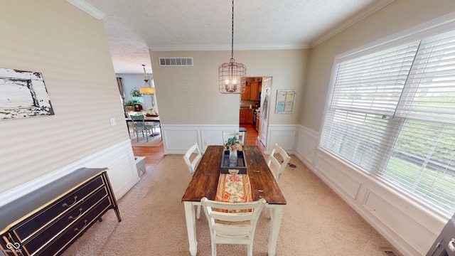 18247 Kinder Oak Dr, Noblesville, IN 46062 - dining area with a textured ceiling, a chandelier, a wainscoted wall, light carpet, and crown molding