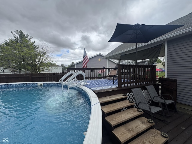 view of swimming pool with a fenced backyard and a deck