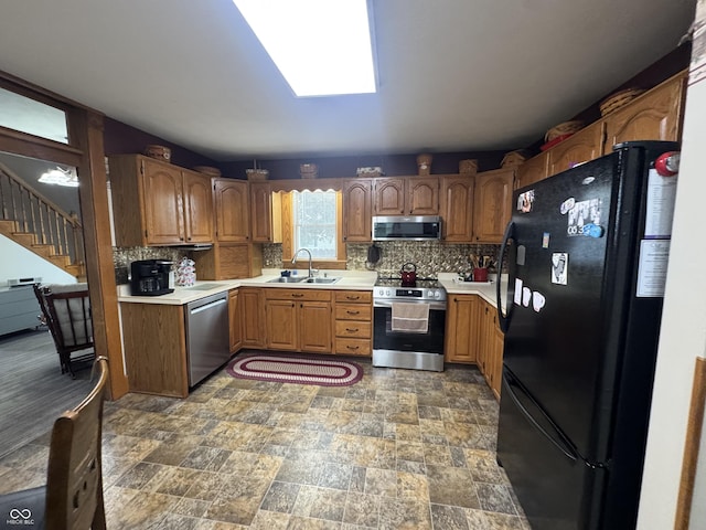 kitchen featuring stainless steel appliances, a sink, decorative backsplash, and light countertops