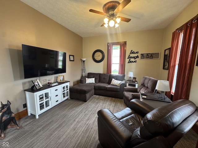 living room with a ceiling fan, dark carpet, a textured ceiling, and baseboards