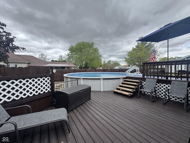 wooden terrace featuring an outdoor pool and fence