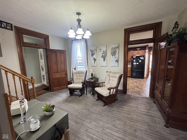 sitting room with a chandelier, stairs, baseboards, a textured ceiling, and carpet floors