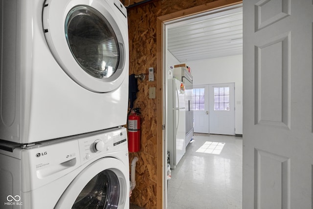 laundry area with stacked washer / dryer, laundry area, and light floors