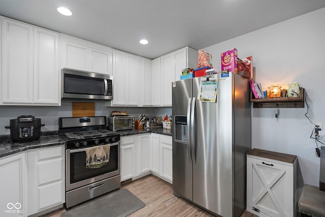 kitchen with light wood-type flooring, a toaster, recessed lighting, white cabinetry, and appliances with stainless steel finishes