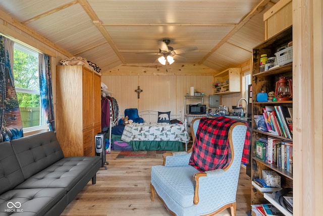 bedroom with light wood-type flooring, vaulted ceiling, and wooden walls